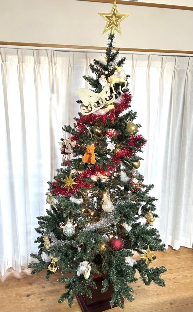 赤いガーランドとゴールドのオーナメントで飾り付けたクリスマスツリー全体の写真。トップスターやサンタ飾りも配置した完成形。
