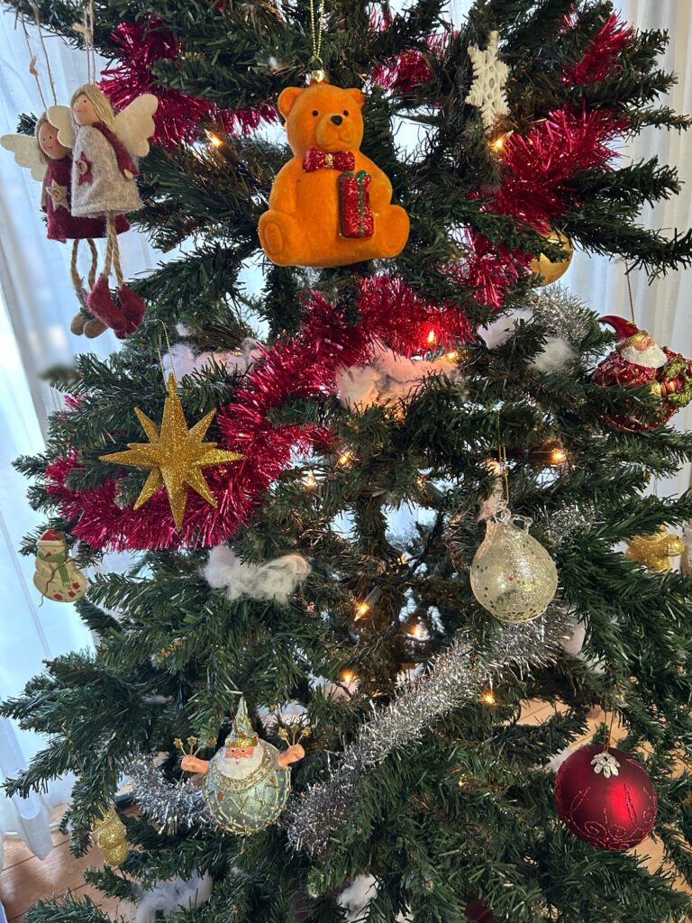 クリスマスツリーに飾った天使、クマ、星のオーナメントのクローズアップ写真。色や大きさのバランスを取った飾り方の例。