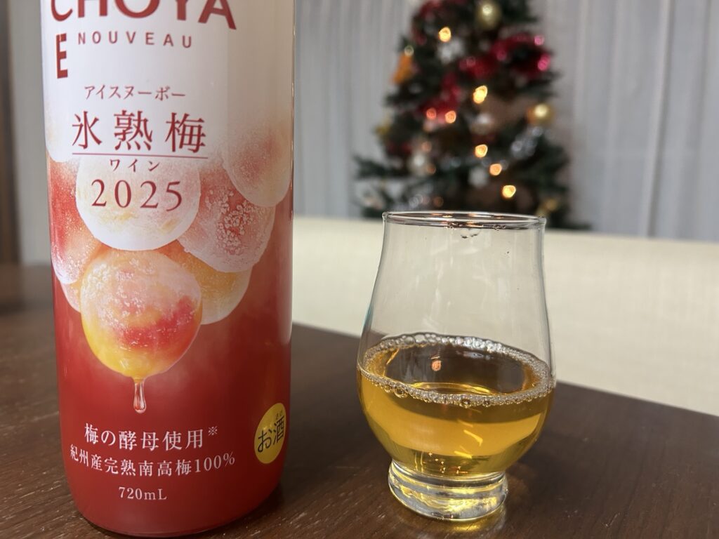 クリスマスツリーを背景にしたCHOYA氷熟梅ワインとグラスの写真
